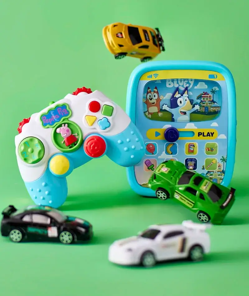 A colourful children’s toy setup featuring a Peppa Pig themed controller, a Bluey tablet toy screen, and several small toy cars arranged on a bright green background. A colourful children’s toy setup featuring a Peppa Pig themed controller, a Bluey tablet toy screen, and several small toy cars arranged on a bright green background.